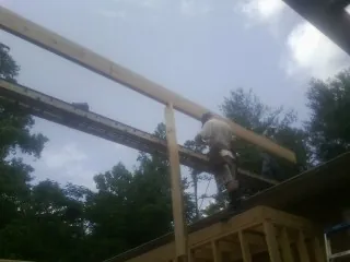 Carpenter setting a ridge beam over a new addition frame — Ice Dam Removal by Roofing Brothers in Manquin