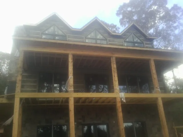 Dormers and porch framing on a large log home under construction — Roof Coating work by our crew in Manquin