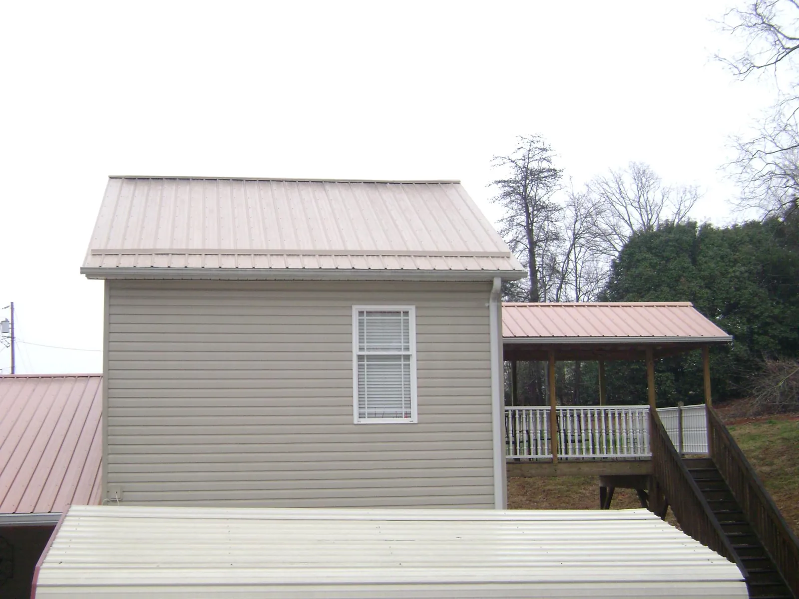 Tan metal roofs on a two story addition and attached porch, from a Roof Replacement job in Manquin
